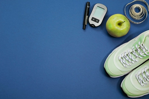 Flat lay with diet diabetes weight loss concept. Sneakers, tape measure, glucometer on a blue