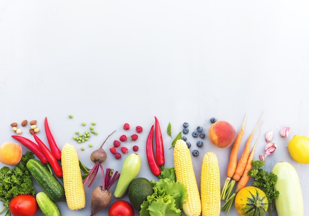 Flat lay with different vegetables, fruits, berries, nuts, spices, herbs, olive oil. Copy space area for some text. Veggies on grey concrete background. Concept of organic bio food healthy eating