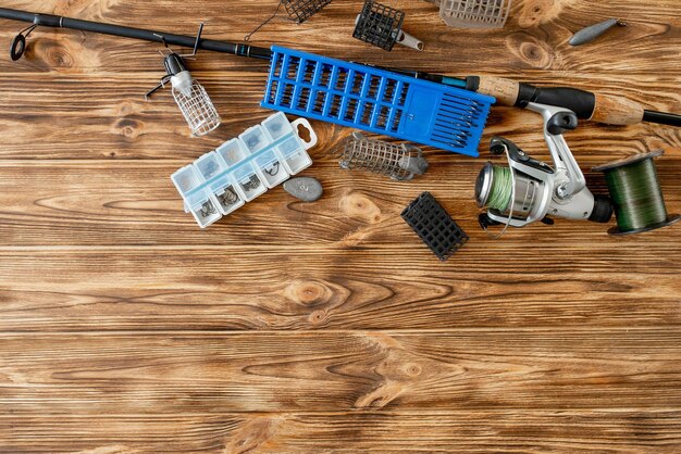 Flat lay with fishing tackle fishing rod and plastic box with fishing tackle and hooks feeders on wooden planks copy space