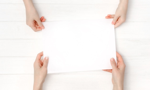 Photo flat lay with hands holding blank sheet of paper