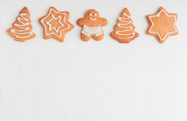 Flat lay with homemade baked gingerbread cookies decorated with sugar icing on white wooden table