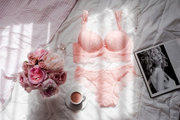 Flat lay con lingerie di pizzo, bouquet di rose, caffè e rivista