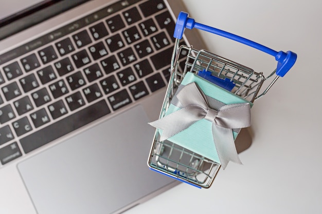 Flat lay with laptop, grocery cart and gift box