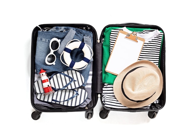 Flat lay with open suitcase with casual clothes for summer vacations over white wall. Summer holidays, travel, tourism, flight luggage concept. Top view