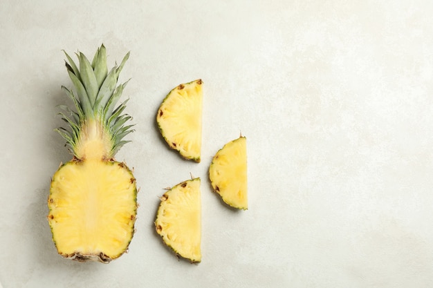 Flat lay with pineapple and slices on white textured background