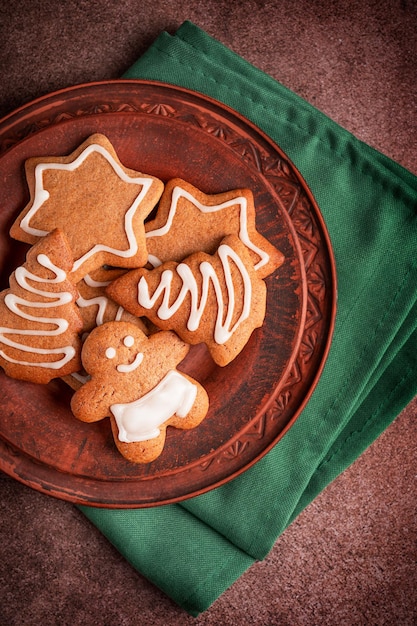 Flat lay with plate of homemade sweet tasty gingerbread cookies with sugar icing served on table