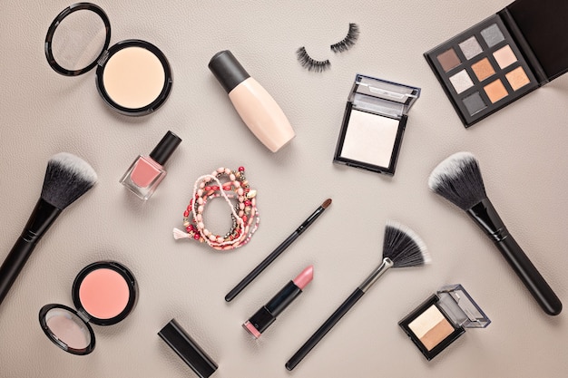 Flat lay with set of professional decorative cosmetics, makeup tools and woman accessories over gray wall with copy space. Beauty blog, fashion, party and shopping concept. Top view