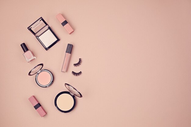 Flat lay with set of professional decorative cosmetics, makeup tools and woman spring, summer accessories over pink wall with copy space. Beauty blog, fashion, party, shopping concept. Top view