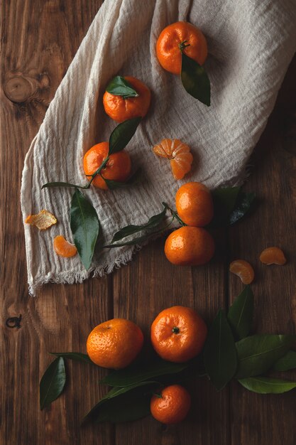 Flat lay with tangerines with leaflets on a wooden background.