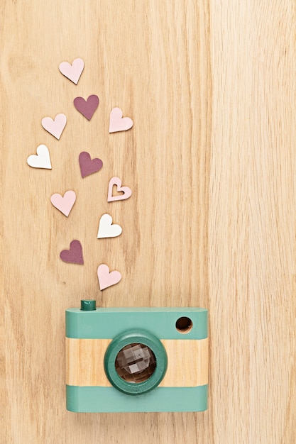 Flat lay with toy wooden camera and hearts over wooden wall. Social media, posts, likes, followers, online photography classes concept. Top view, copy space.