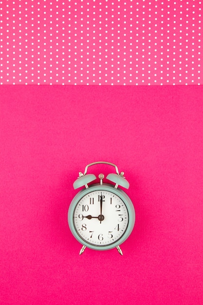 Flat lay with vintage alarm clock over the pastel background with polka dots