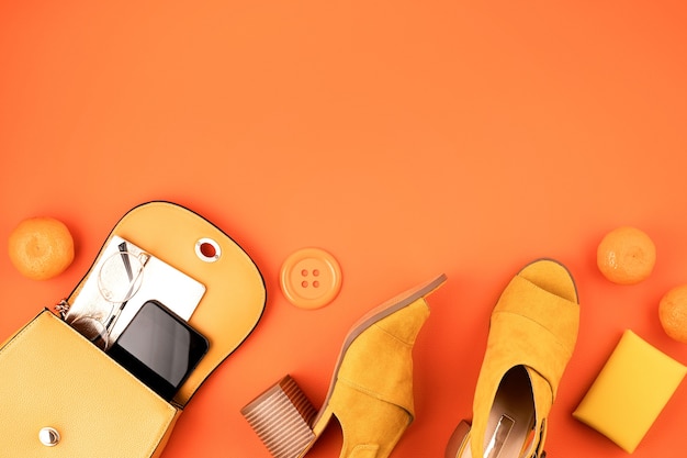 Фото Квартира лежала с женскими модными аксессуарами желтого цвета над оранжевой кожаной текстурированной стеной. мода, онлайн-блог о красоте, летний стиль, шоппинг и концепция тенденций