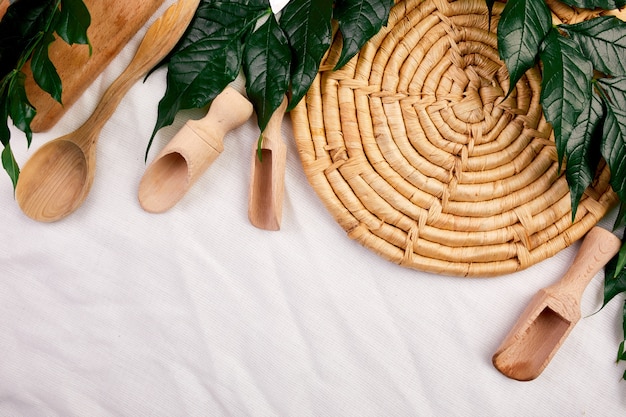 Flat lay with wooden kitchen utensils with green leaves, cooking tools on textile background, ktchenware collection captured from above, mockup, frame.