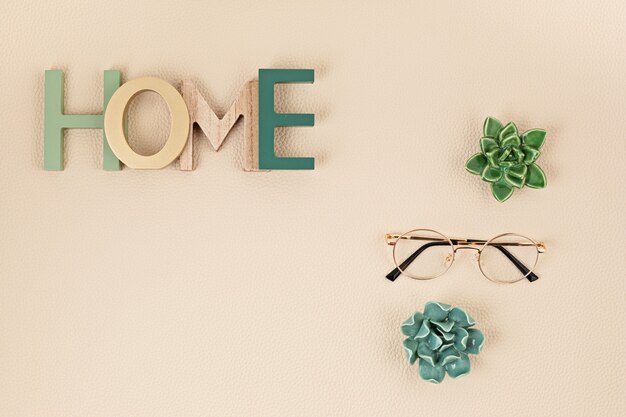 Photo flat lay with wooden word home over neutral beige wall with leather texture. home comfort, decoration minimal concept. top view, copy space