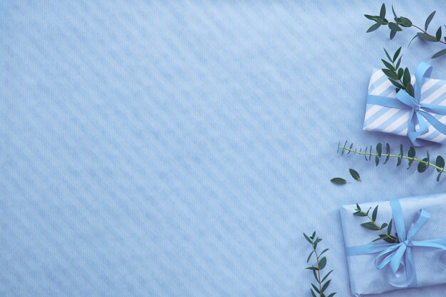 Flat lay with wrapped gift boxes and eucalyptus twigs in light blue hues