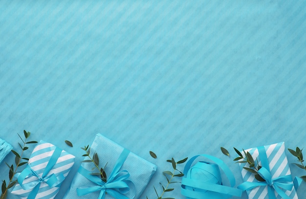 Flat lay with wrapped gift boxes and eucalyptus twigs in light blue hues