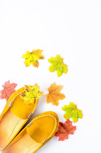 Flat lay with yellow leaves and shoes on white background for cool weather, bright colored fall 