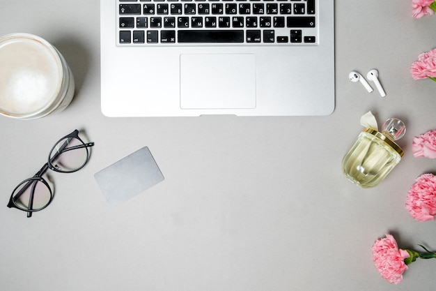 Flat lay woman office desk Workspace with laptop pink carnation stationery on white table Top view