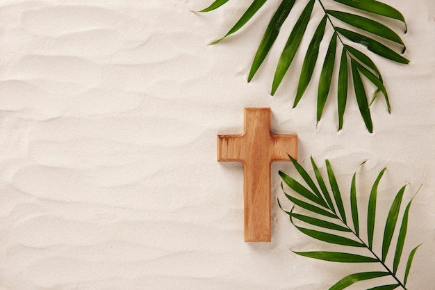 写真 フラットレイ木製の十字架と砂の上の葉