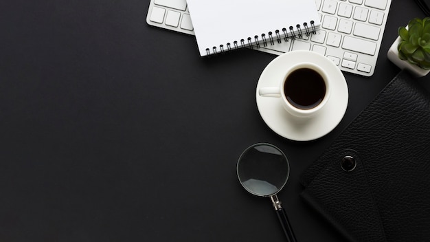 Foto disposizione piana della scrivania con tazza di caffè e lente d'ingrandimento