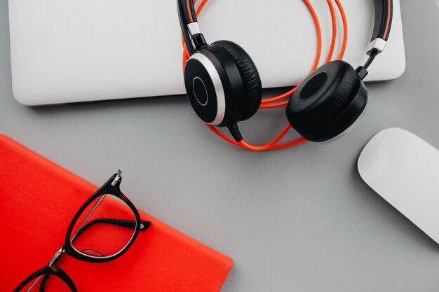 Flat lay workdesk with eyeglasses notebook and red diary on grey background