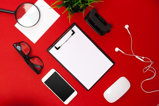 Flat lay of working space supplies on red background