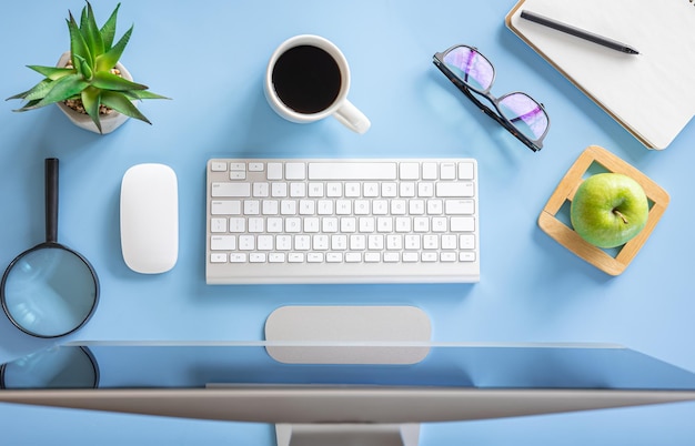 Flat lay workplace computer on a blue background top view