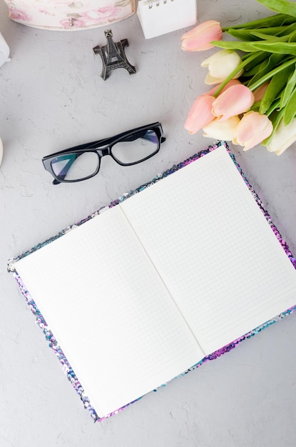 Flat lay workplace with fresh tulips bouquet with empty notebook