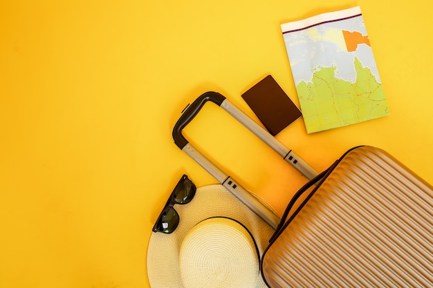 Foto valigia piana di disposizione piana con gli occhiali da sole degli accessori del viaggiatore su fondo giallo