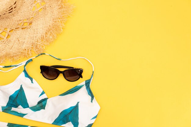 Flat lay yellow suitcase with traveler accessories on yellow background.