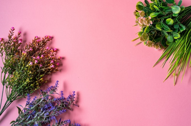 Layout piatto di rami di fiori secchi su sfondo rosa, vista dall'alto, spazio copia.