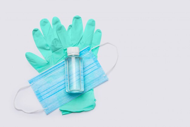 flat layout of hygiene items - latex gloves, mask and hand sanitizer over light grey background