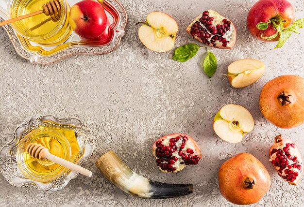 Flat layout top view gray concrete background with apples pomegranate horn honey in a silver bowl New Year Rosh Hashanah