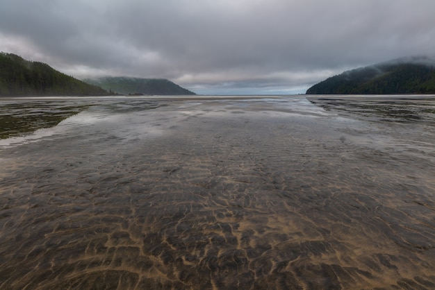 Flat open beach with sand and no people with distance cloud, looks relaxing place on vancouver island, british columbia, canada.