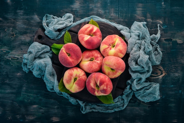 Flat peach with green leaves On a black wooden background Top view Free space for your text