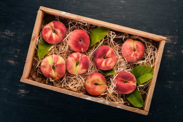 Flat peach in a wooden box On a black wooden background Top view Free space for your text