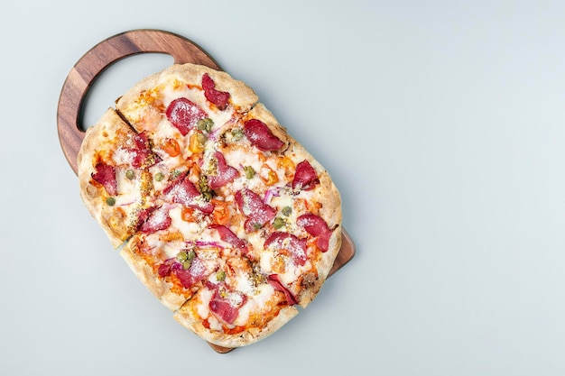 Flat pizza on a wooden pizza board top view Grey background