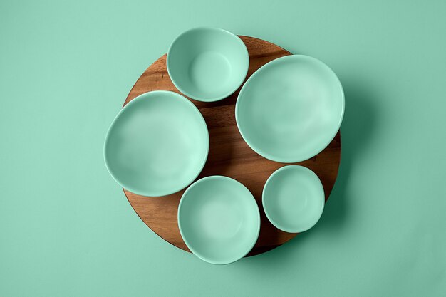 Flat set of empty bowls painted in the fashionable color of 2020 neo mint on the background of the same shade.