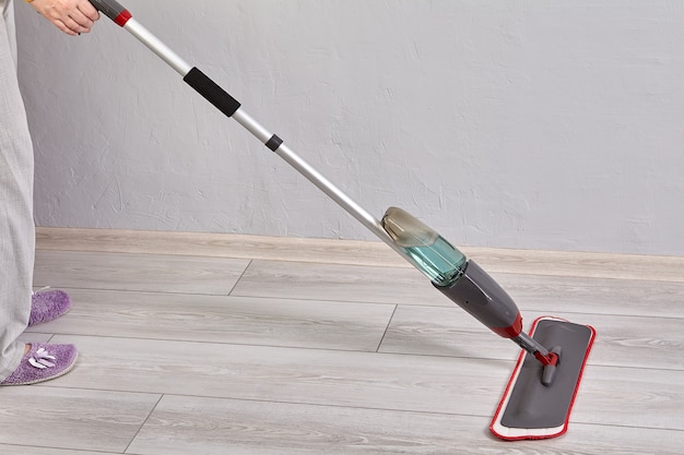 Flat spray mop involve microfiber head for wood floor cleaning with trigger of water spraying located at end of handle.