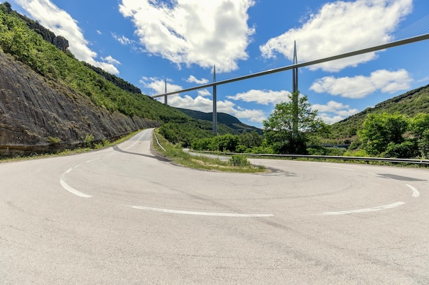 Flat straight Millau Viaduct above and old curly country road D41 Aveyron Occitania