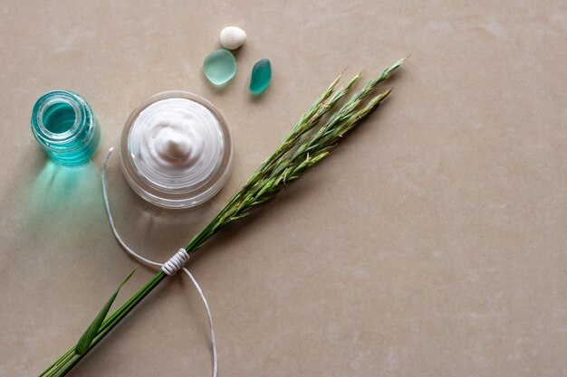 Flat view A jar of cream spikelets with a white rope two glass dolls and a pebble Selective focus