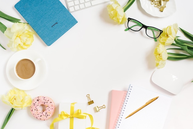 Flat workspace of a lady blogger or freelancer with a notepad and yellow tulips and an office