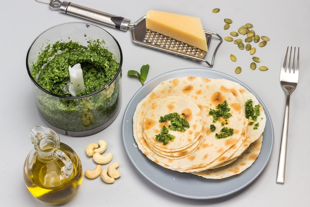 Flatbread on ceramic plate Grinded greens in blender