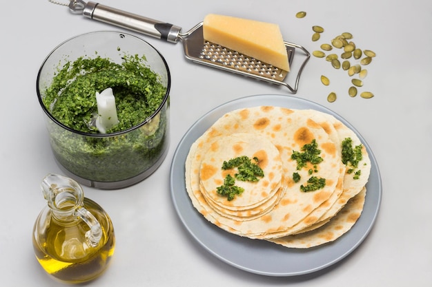 Photo flatbread on ceramic plate grinded greens in blender