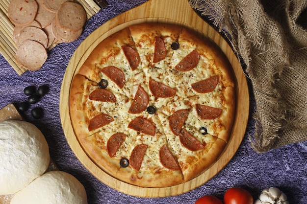 Flatbread pizza garnished with fresh angular on wooden pizza board top view Dark stone background