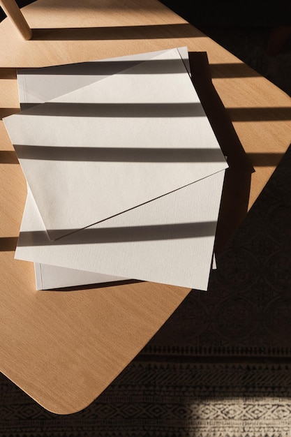 Foto flatlay di un modello di invito in stile parigino estetico carta bianca con spazio di copia mockup sedia in legno in condizioni di luce solare intensa vista dall'alto piatta