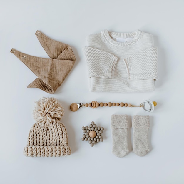 Flatlay aesthetic Scandinavian newborn baby clothes accessories toys collage on white background Trendy elegant neutral pastel colour infant fashion set Top view