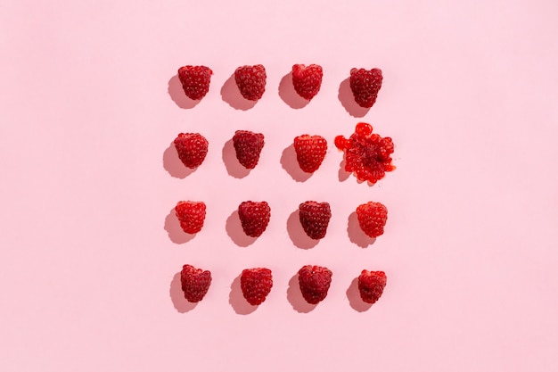 Flatlay of arranged raspberries on pink
