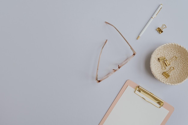 Flatlay blank copy space Clipboard glasses clips on rattan plate on pastel background Home office desk workspace Aesthetic business work template Flat lay top view