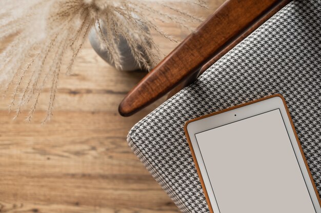 Flatlay of blank screen tablet pad on retro chair. Home office desk workspace